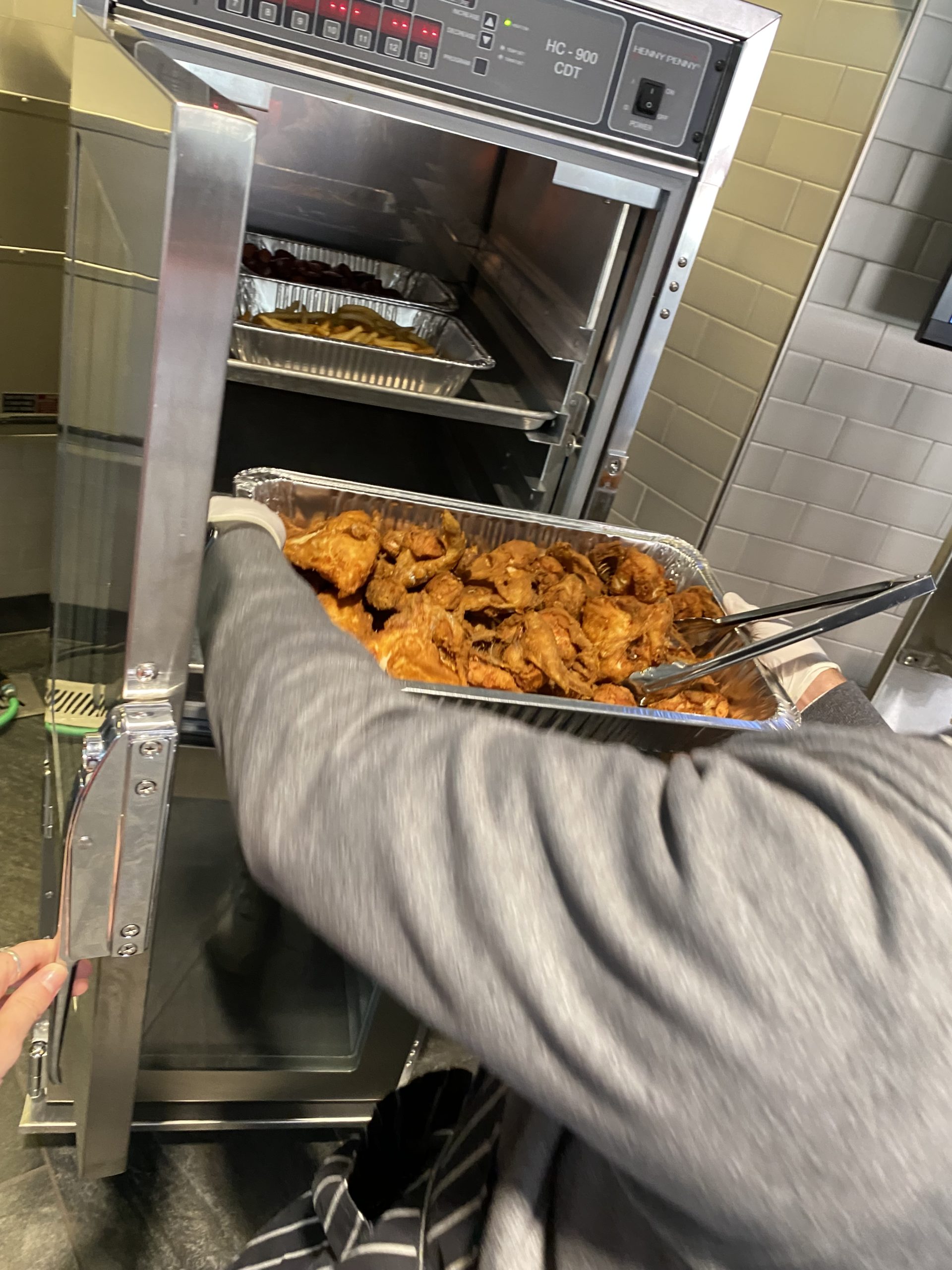 Pan of fried chicken being placed into a Henny Penny Holding Cabinet