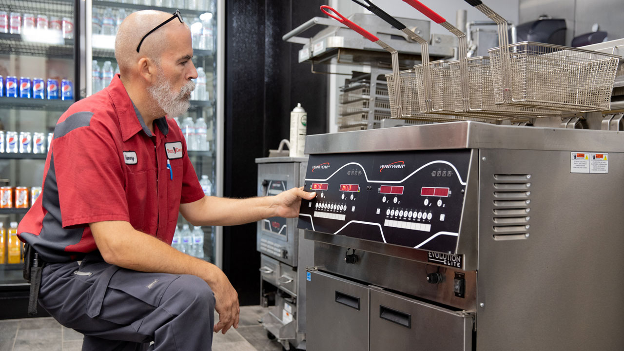 Henny Penny service technician looking at a Henny Penny fryer